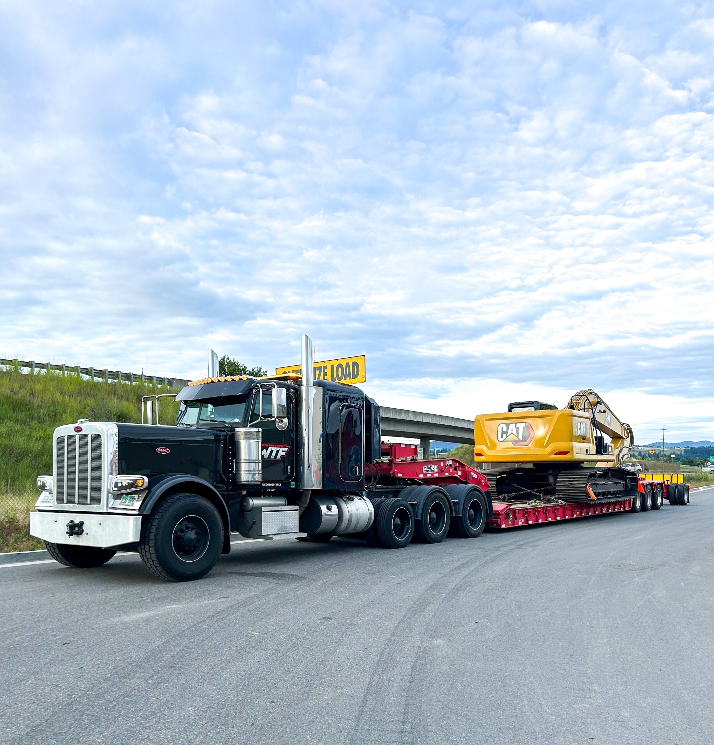 8 axle RGN hauling a heavy CAT excavator